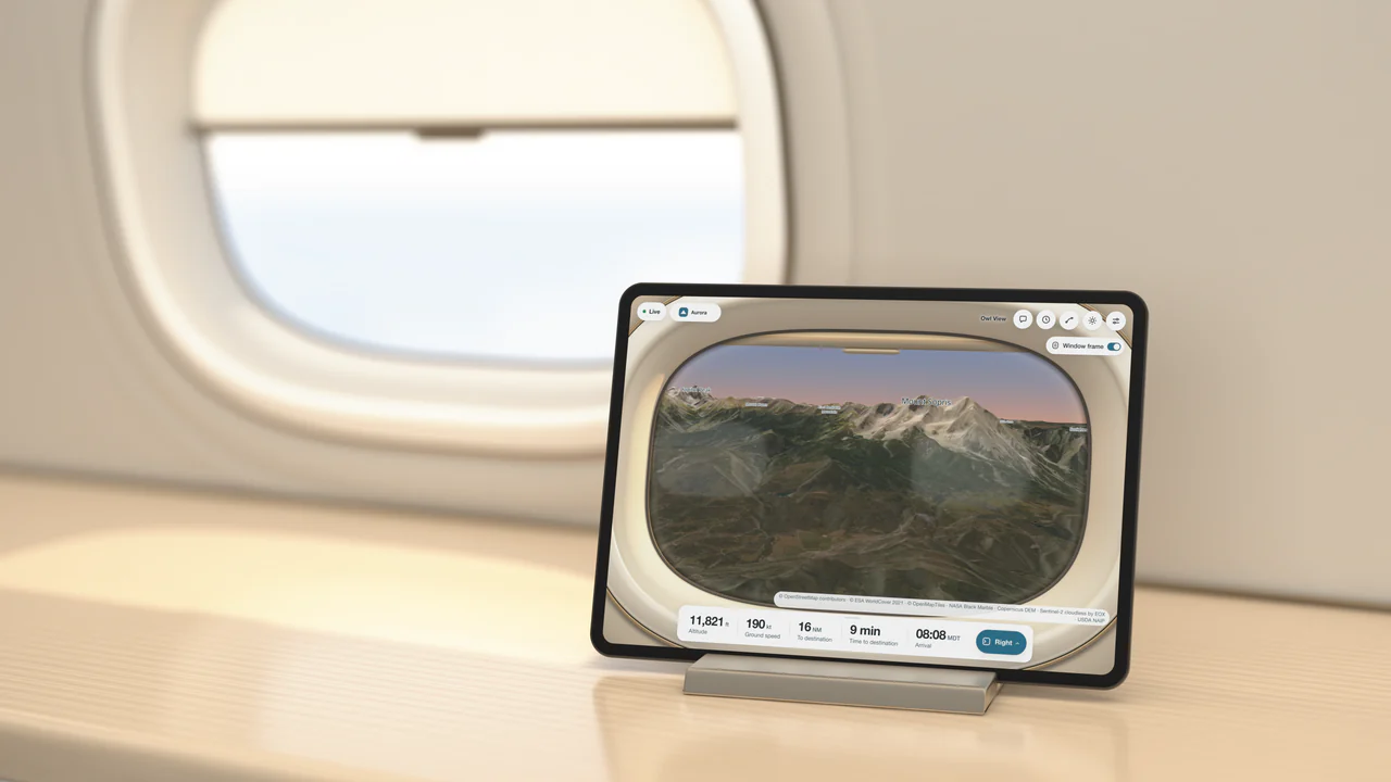 A rendered business-jet cabin: a tablet in a stand on a pale oak ledge beside a cabin window with its shade half drawn, showing Owl View's right window view of Mount Sopris